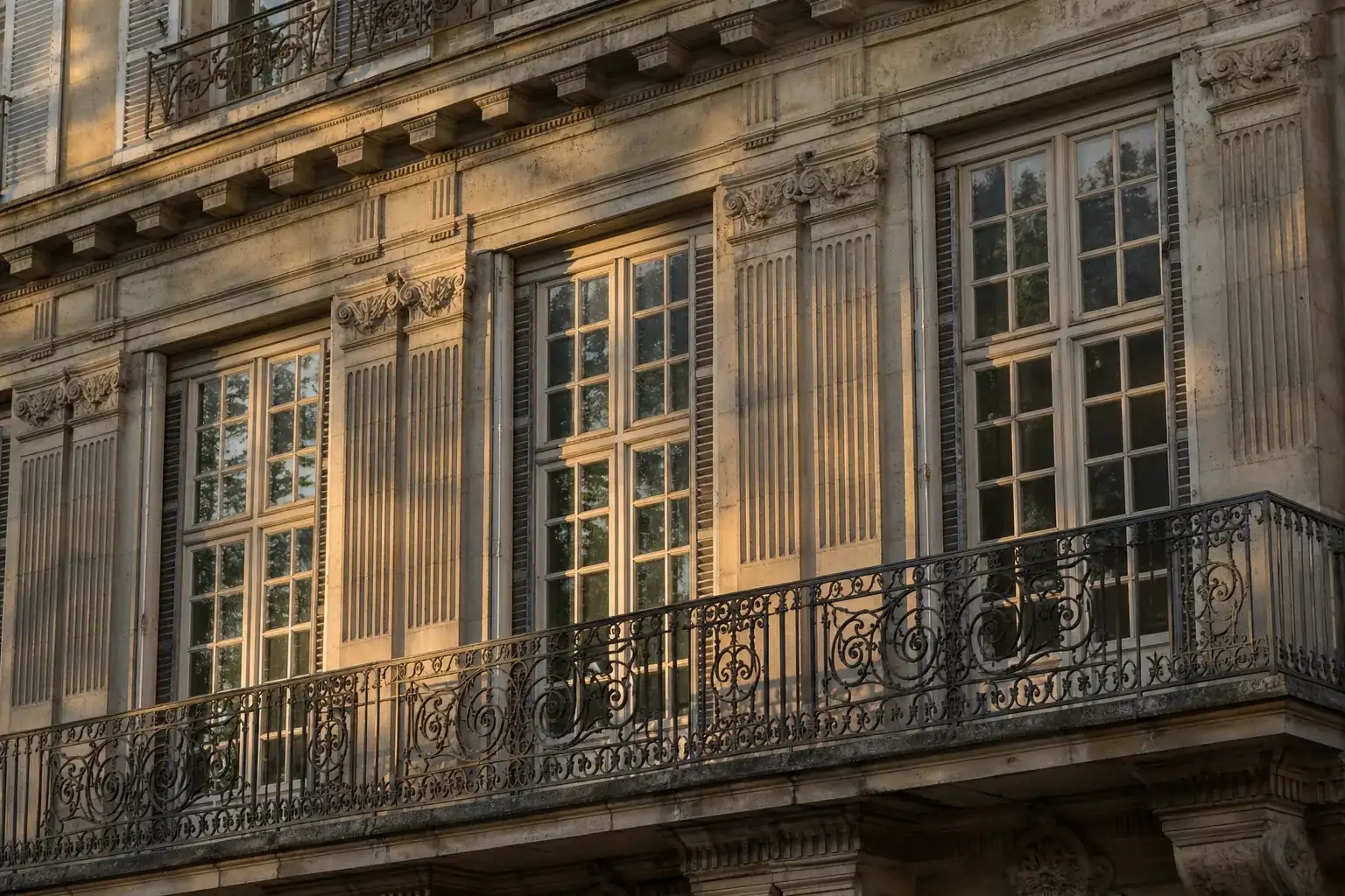 Détail de façade d’immeuble ancien avec fenêtres à petits carreaux et balcon filant